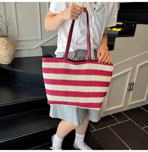 Dettaglio della borsa tote intrecciata a righe rosse e bianche con manici rossi lunghi