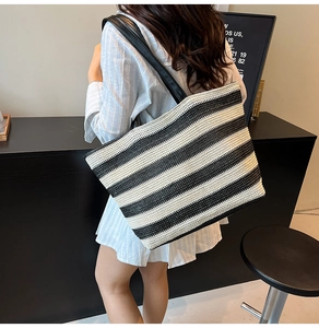 Dettaglio della borsa tote intrecciata a righe bianche e nere con manici in ecopelle
