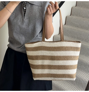 Dettaglio della borsa tote intrecciata a righe con manici in finta pelle marrone per vacanze