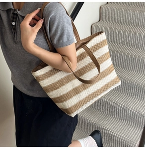 Dettaglio di una borsa tote intrecciata a righe beige e marroni con manici in pelle