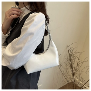 Close-up of a white patent leather crescent bag showing smooth texture and metal zipper