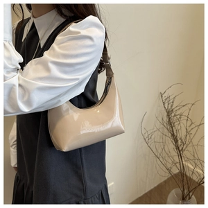 Detail of glossy beige patent leather hobo bag with adjustable strap and silver zipper