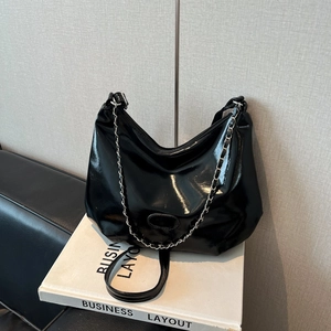 Détail du sac croissant en cuir verni noir brillant avec chaîne argentée et ferrures