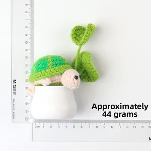 Top view of handmade crochet turtle doll in white pot with measuring rulers and 44g weight
