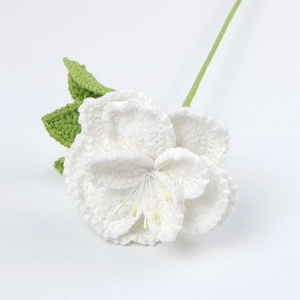 Detailed macro view of handmade white crochet rose with green leaves and knitted texture