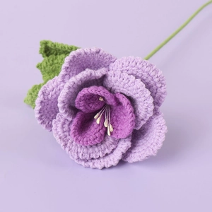 Detailed close-up of handmade crochet purple rose with intricate knit petals and green leaf