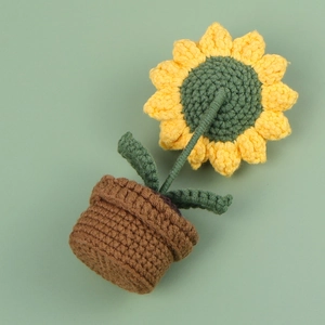 Macro detail of hand-knitted sunflower crochet decor in a brown pot for car dashboard