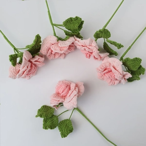 Set mit fünf handgefertigten rosa Häkelrosen mit grünen Stielen auf weißem Grund