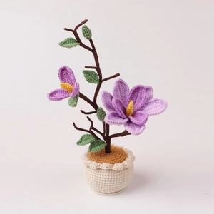 Detailed close-up of handmade crochet purple magnolia flower in a white knitted pot