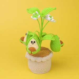Handmade crochet avocado potted plant ornament with cute smiling faces on yellow background