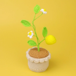 Handmade crochet lemon potted plant with bright yellow fruit and green leaves on yellow base