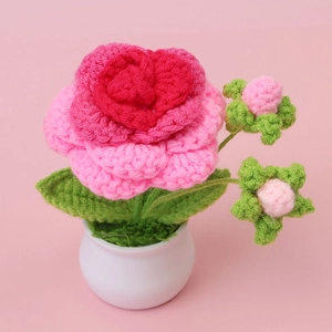 Hand-crocheted pink rose potted plant with green leaves in white ceramic base