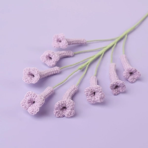 Gros plan de fleurs en crochet faites main avec pétales texturés et tiges vertes délicates
