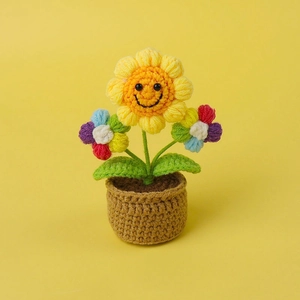Detail of hand-knitted sunflower crochet plant with a smiling face in a brown pot
