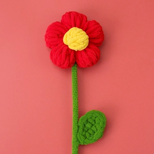 Macro detail of a handcrafted crochet puff flower made from soft red and yellow yarn