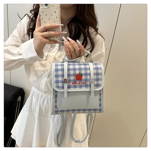 Detail of blue plaid crossbody bag featuring red apple embroidery and adjustable strap