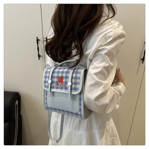 Detail of blue plaid mini backpack featuring red apple embroidery and adjustable straps