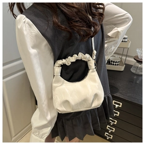 Detail of cream pleated cloud bag with scrunched handle and adjustable crossbody strap