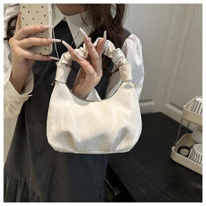Detail of a creamy white pleated cloud bag showing soft faux leather texture and handle