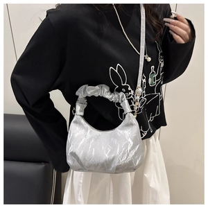 Detail of light blue pleated cloud bag with metallic finish and adjustable shoulder strap