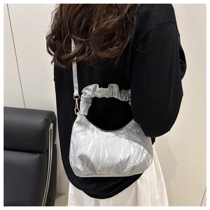 Detail of silver pleated crescent bag with metallic finish and ruffled handle design
