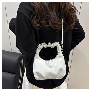 Close-up of white crescent bag with glossy crinkled texture and ruched handle