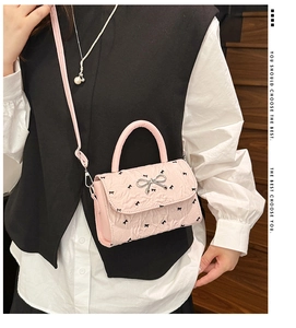 Détail du sac bandoulière plissé rose avec un nœud argenté et une fine bandoulière