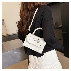 Détail du sac à main en cuir PU blanc avec imprimés nœuds noirs et fermoir argenté élégant