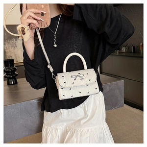 Détail du sac bandoulière en cuir PU blanc avec nœuds noirs et fermoir argenté