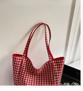 Close-up of red gingham canvas tote bag with fashion label and durable handle detail