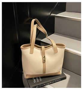 Detail of cream and brown tote bag with wavy opening and gold rotating clasp on steps