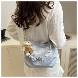 Detail showing light blue ruffled shoulder bag with a cute brown bear charm