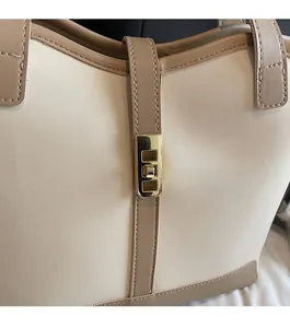 Detail of golden metal clasp on a beige and light brown crossbody bag for women