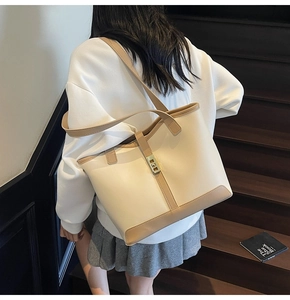 Rear view of a model wearing a large cream and khaki tote bag on wooden stairs