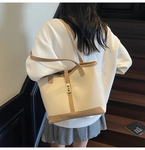 Detail of tan and cream tote bag with gold lock buckle and long shoulder straps