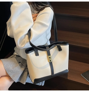 Detail of color-block tote bag featuring black trim and gold twist-lock closure
