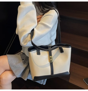 Detail of a large color-block tote bag with beige canvas, black leather trim and gold lock