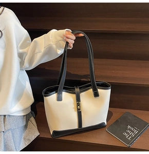 Detail of contrast stitching and gold metal twist-lock on a minimalist tote bag