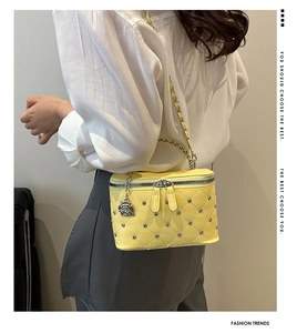 Detail of yellow quilted box bag with silver studs and a metal rose zipper charm
