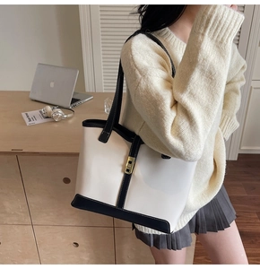 Detail of a black and white large tote bag with gold buckle and adjustable strap