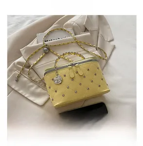 Detail of yellow quilted leather bag with silver studs and metal chain strap