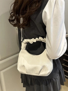 Minimalist white leather half-moon cloud bag with pleated handle shown on a model