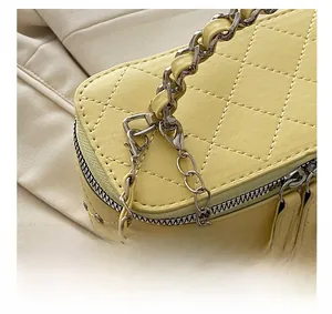 Detail view of yellow quilted leather bag with silver chain strap and metal hardware