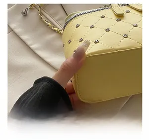 Detail of yellow quilted bag with gold rivets and leather woven chain strap