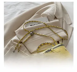 Detail of yellow quilted handbag with gold studs, chain strap, and camellia charm