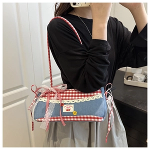 Detail of blue denim underarm bag with red plaid trim and white lace accents