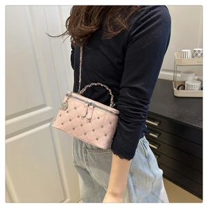 Detail view of pink quilted handbag with gold chain strap and metal ring handle