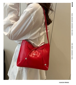 Detail der roten Beuteltasche mit Schleifenknoten und Logo auf weißem Sommerkleid