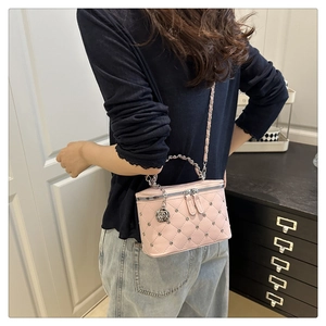 Detail of pink quilted vanity bag featuring silver rivets and a rose pendant charm