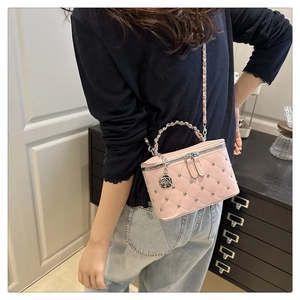 Close-up of pink quilted bucket bag with silver metal chain and rose pendant detail